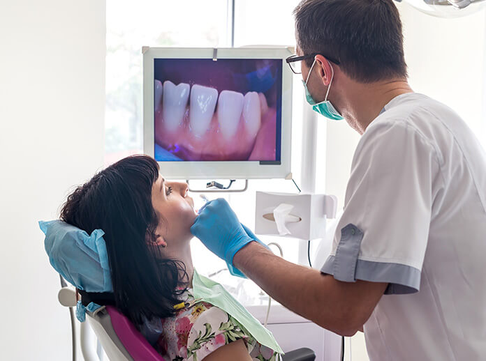 dentist examining a patient's teeth with the use of an intraoral camera