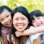 Mom smiles with her 2 daughters before visiting their family dentist in Aurora, CO