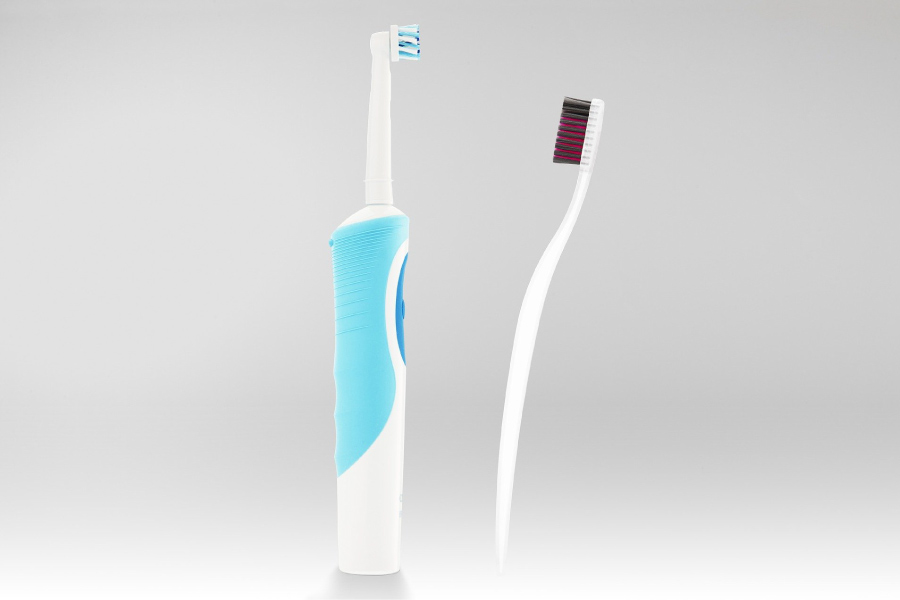 Photo of an electric toothbrush facing off with a manual toothbrush.