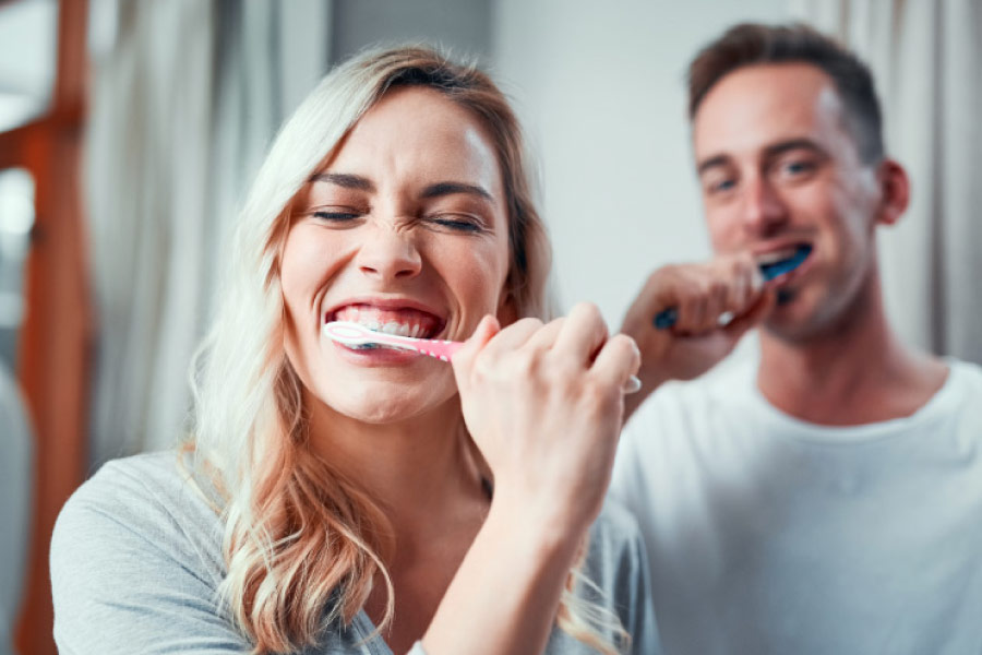 Couple brushing their teeth to improve dental hygiene.